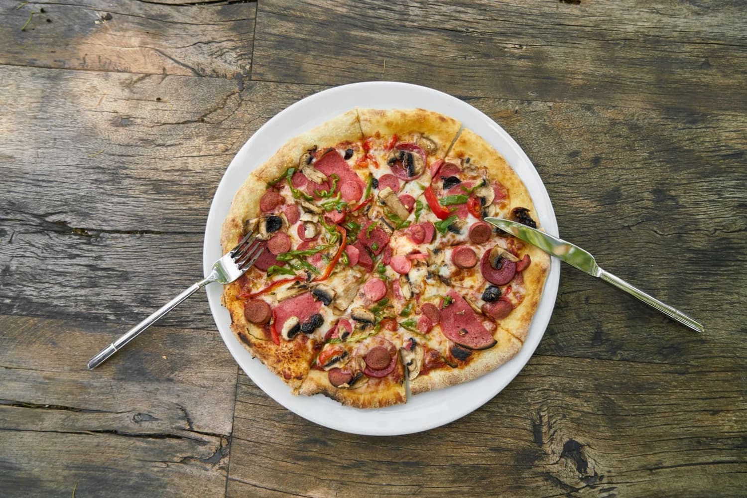A pizza topped with a fusion of toppings served on a white plate