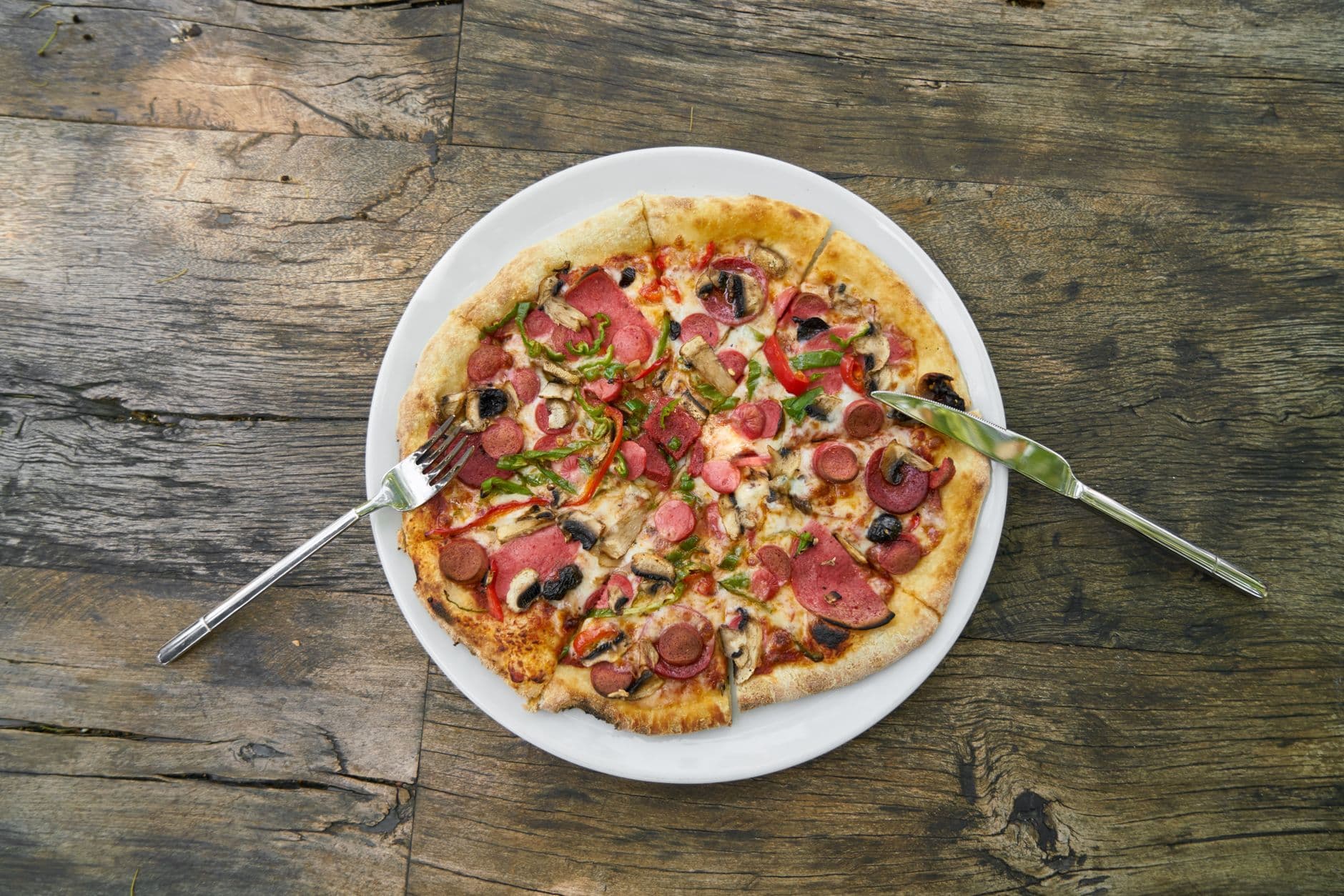 A pizza topped with a fusion of toppings served on a white plate