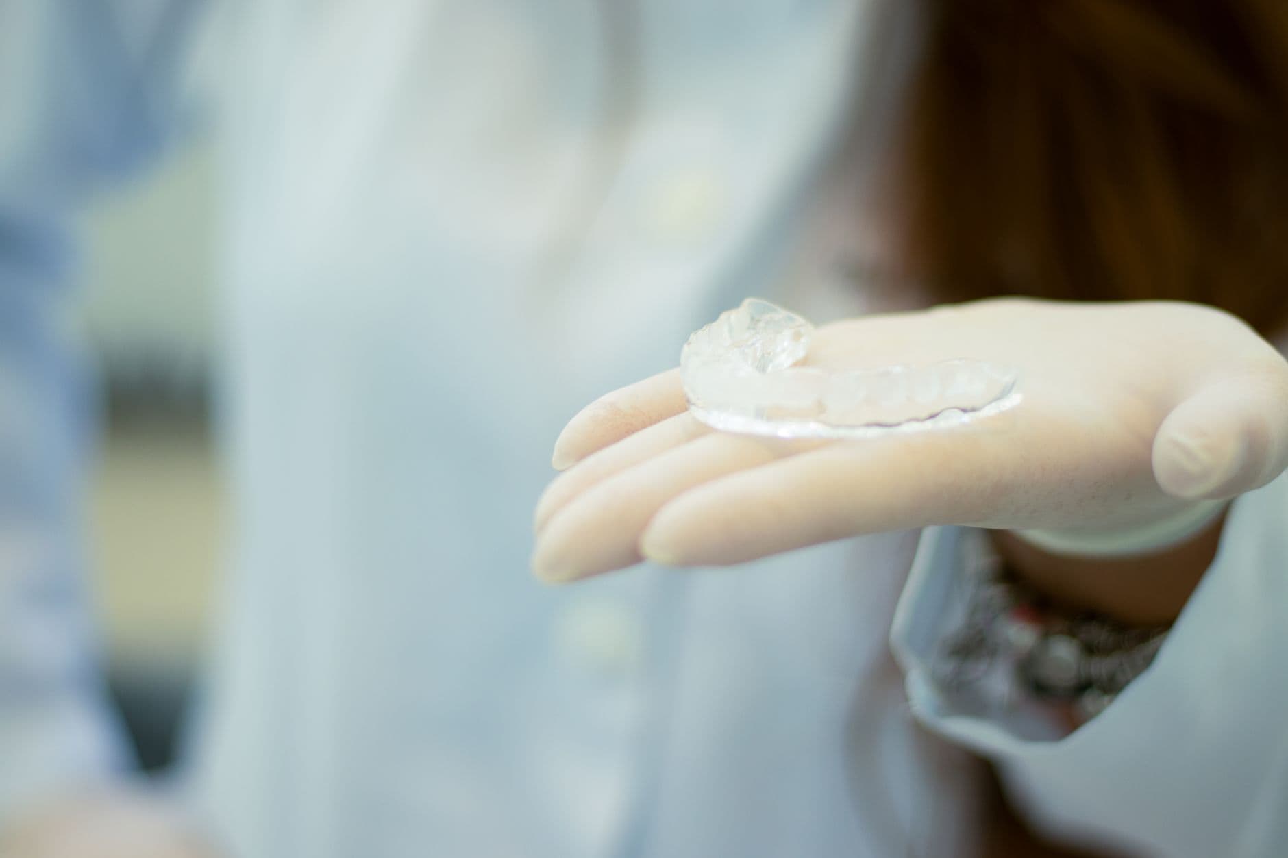 A clear dental mouthguard held in a gloved hand