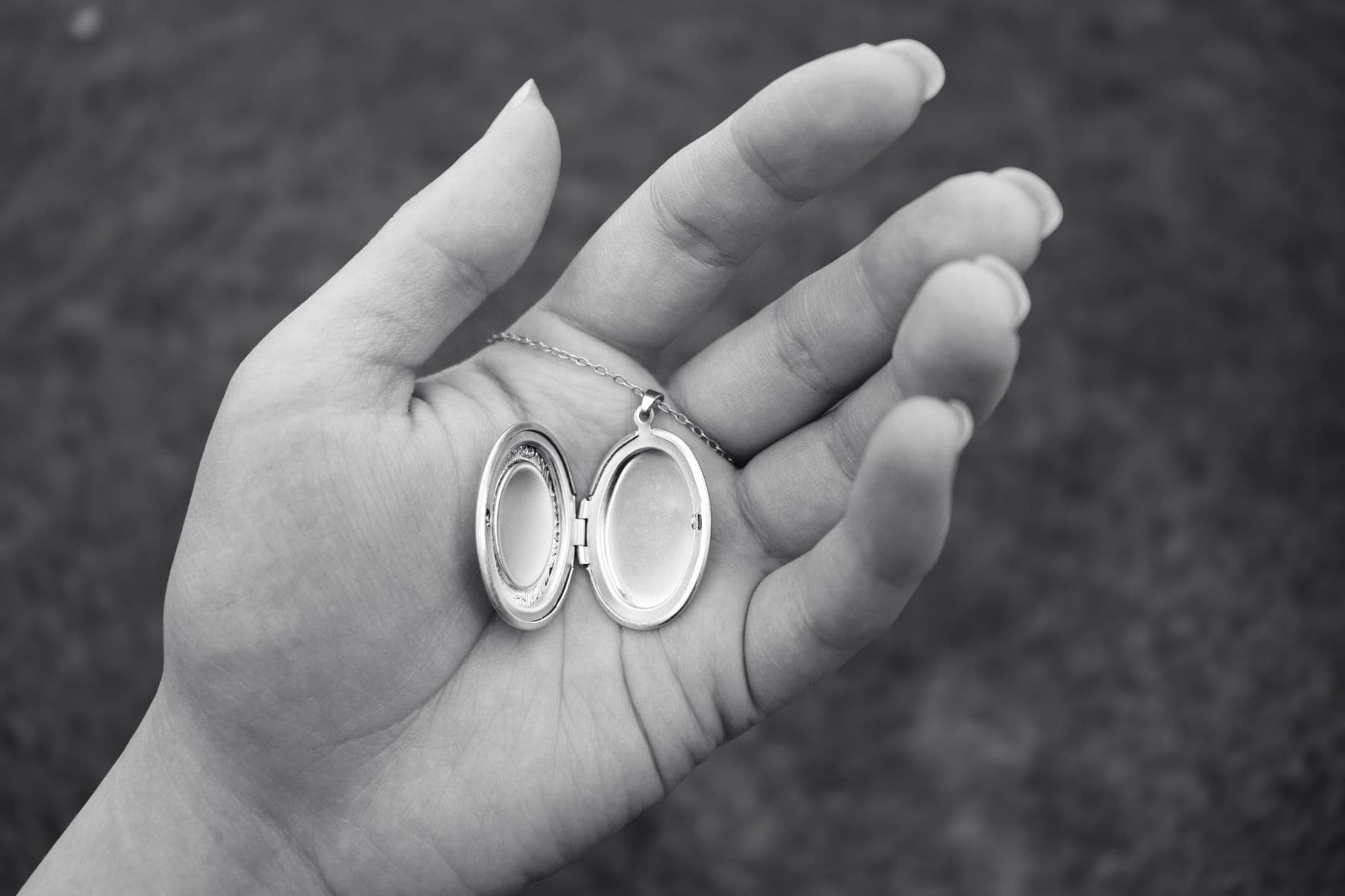A hand holding an open silver locket necklace